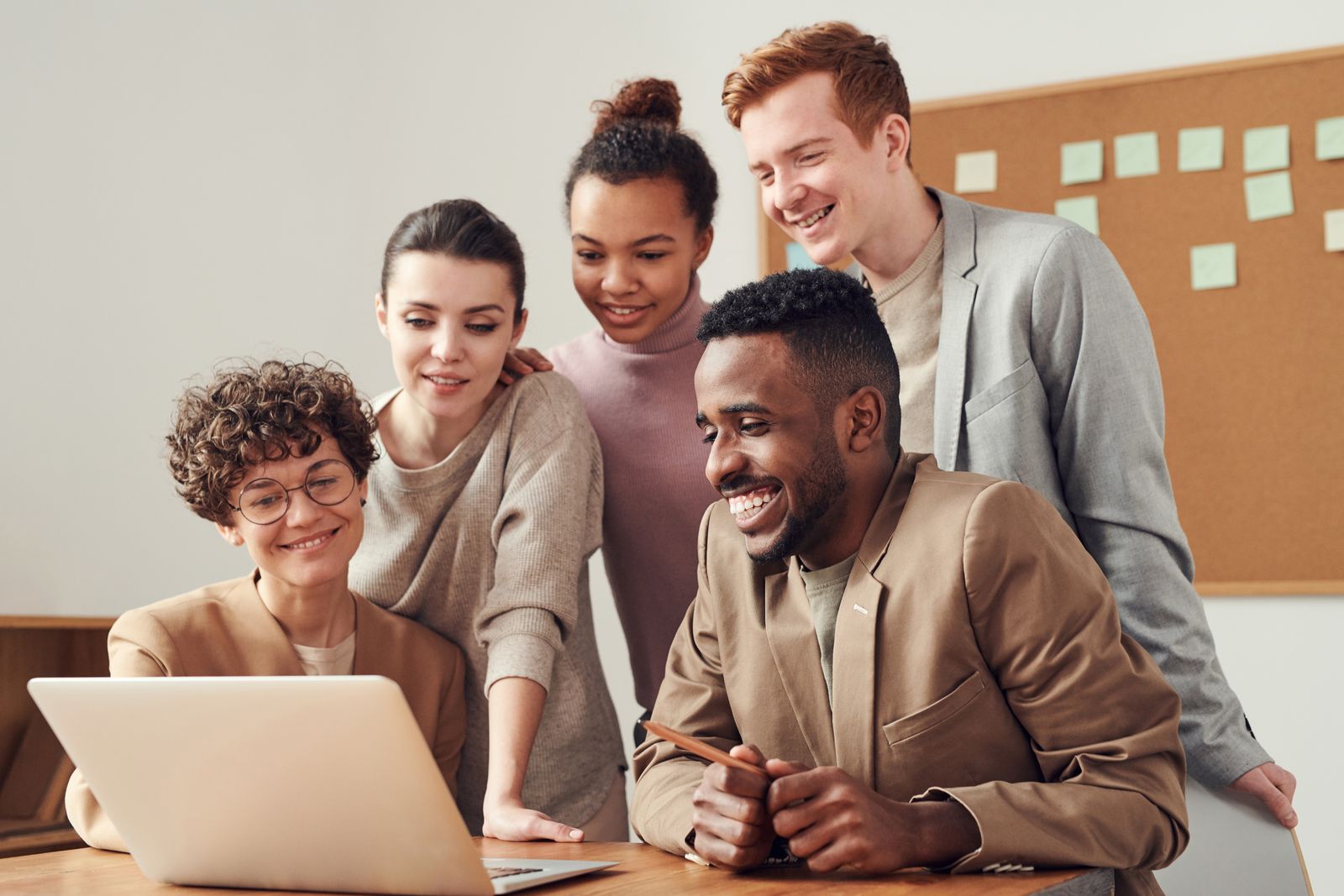 A group of colleagues smiling around a laptop